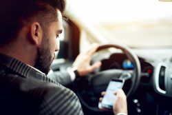 Man,Looking,At,Mobile,Phone,While,Driving,A,Car.